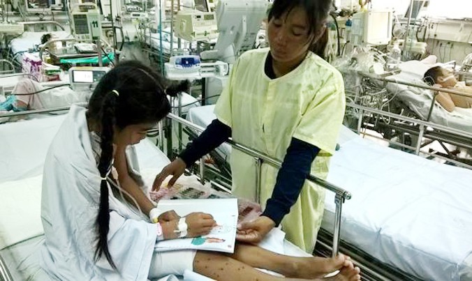“Cô bé mai rùa” đang tô màu bên mẹ tại khoa hồi sức ngoại Bệnh viện Nhi đồng 1. Ảnh do bệnh viện cung cấp.