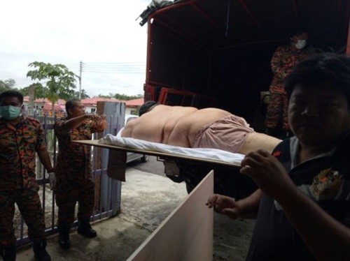 Người đàn ông Malaysia béo phì được đưa lên xe tải đến bệnh viện cấp cứu. Ảnh: NST.