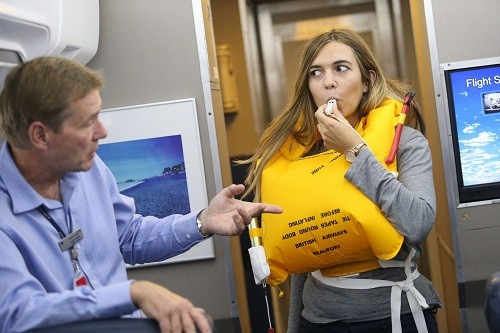 Nữ tiếp viên luyện tập cách hướng dẫn sử dụng áo phao trên máy bay. Ảnh minh họa: British Airways.