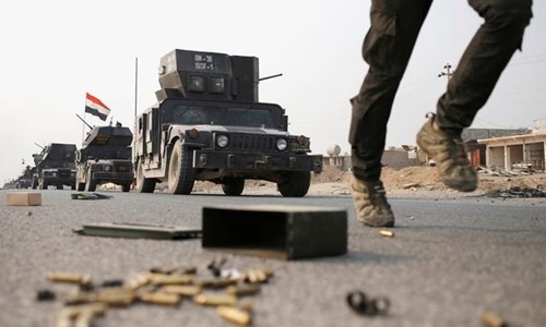 Một binh sĩ Iraq lao về hướng thành phố Mosul với các xe quân sự phía sau. Ảnh: Reuters.