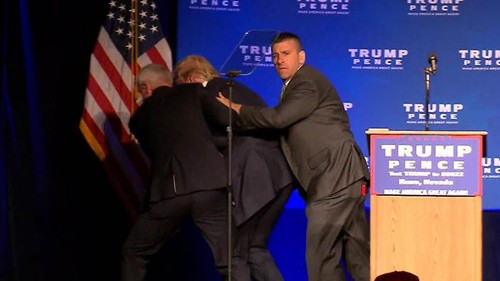 Ông Trump được các nhân viên an ninh đưa về phía sau sân khấu khi đang phát biểu. Ảnh: Reuters.