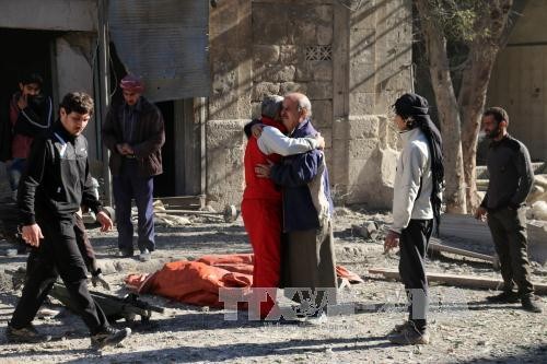 Nhân viên dân sự Syria an ủi một thân nhân nạn nhân vụ không kích và nã pháo tại Aleppo ngày 19/11. Ảnh: AFP/TTXVN.