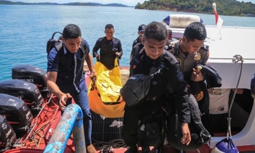 Cảnh sát Indonesia mang túi đựng xác và mảnh vụn máy bay lên bờ. Ảnh: AFP.