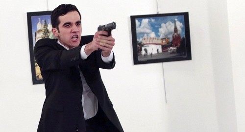 Mevlut Mert Altintas chĩa súng tại phòng triển lãm ảnh. Ảnh: AP.