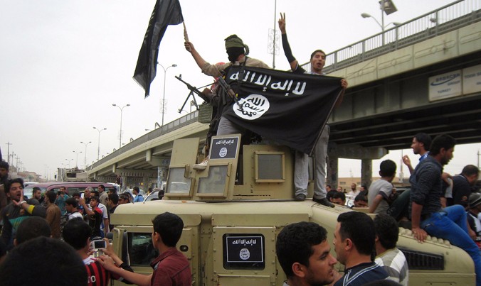 Phiến quân vẫy cờ đen khi đi tuần tra trên xe bọc thép lấy từ quân đội Iraq. Ảnh: AP.