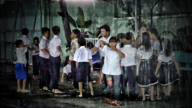 Các em phải đội mưa để đến trường làm lễ khai giảng.