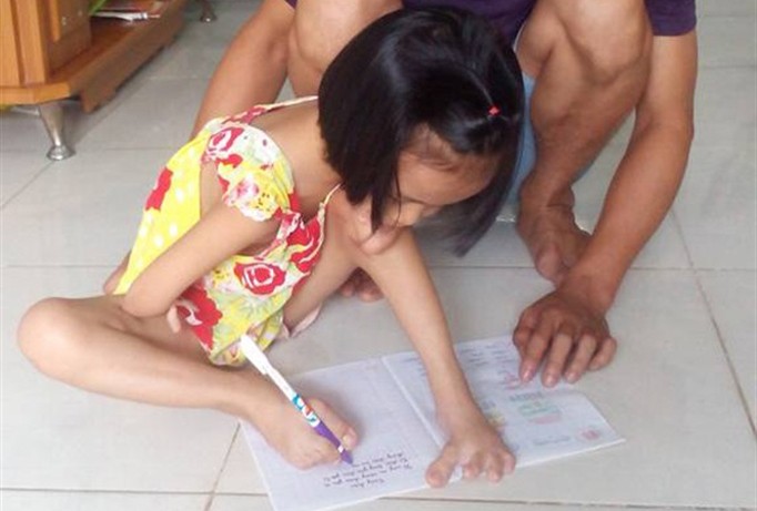 Cảm phục nghị lực bé gái 7 tuổi dùng chân viết để được đi học