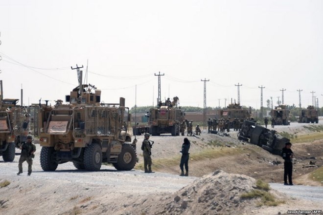 Những người lính NATO theo dõi đống đổ nát của xe tại nơi xảy ra cuộc tấn công ở Kandahar ngày 15/9 vừa qua. Nguồn: AFP.