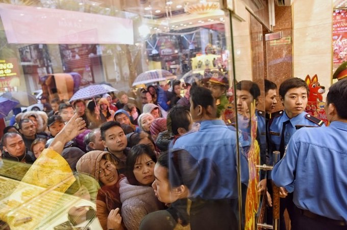 Nhiều người đội mưa, che ô chờ kín đặc bên ngoài cửa hàng vàng.