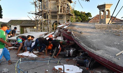 Lực lượng cứu hộ và người dân tìm cách tiếp cận người còn sống và các thi thể dưới đống đổ nát trên đảo Lom bok hôm 5/8. Ảnh: Reuters.