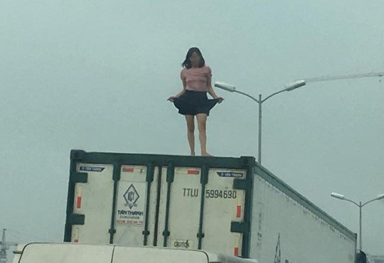 Người phụ nữ mặc váy ngắn, ca hát nhảy múa trên nóc thùng xe container.