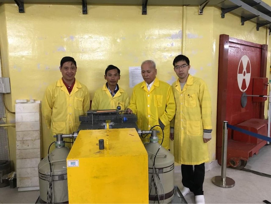 GS Phạm Duy Hiển (thứ hai từ phải) với các nhà khoa học trẻ trước cửa kênh dẫn nơtron lò phản ứng Đà Lạt.
