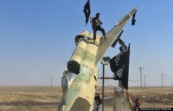 Phiến quân IS đứng trên một xác máy bay chiến đấu bị bắn rơi ở Iraq. Ảnh: AP. 