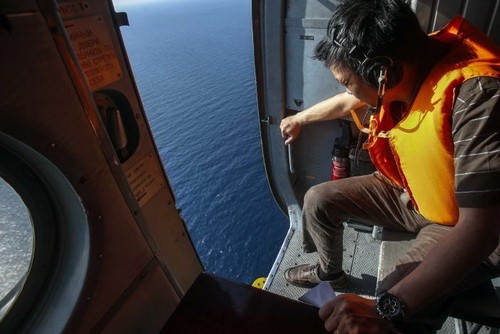 Một nhân viên cứu hộ trên trực thăng của Không quân Việt Nam đang nhìn xuống mặt biển để tìm dấu vết chiếc máy bay của Malaysia mất tích - Ảnh: Reuters
