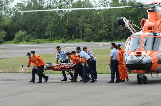 Thành viên đội tìm kiếm, cứu nạn ngày 31/12 đưa thi thể nạn nhân chuyến bay QZ8501 từ trực thăng đến xe cứu thương ở căn cứ không quân Iskandar ở thành phố Pangkalan Bun, tỉnh Trung Kalimantan (Indonesia). Ảnh: Xinhua