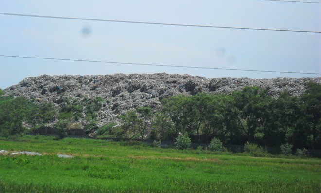 Bãi rác Cồn Quán cao gấp 4 đến 5 lần bờ rào xây. ảnh: Phạm Nhài