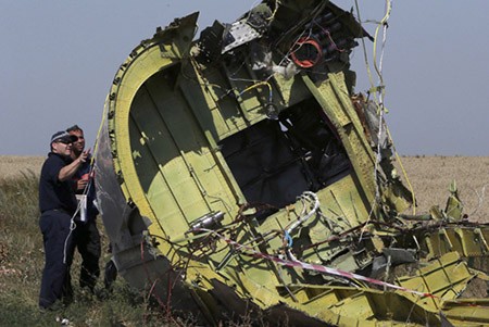 Các chuyên gia quốc tế kiểm tra một mảnh vỡ máy bay tại hiện trường. Ảnh: Reuters.