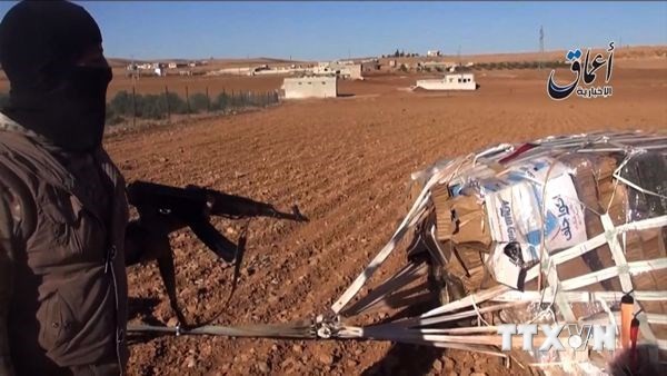 Phiến quân IS bên thùng vũ khí mà Mỹ thả dù gần thành phố Kobane, biên giới Syria- Thổ Nhĩ Kỳ hôm 21/10. (Ảnh: AFP-TTXVN)