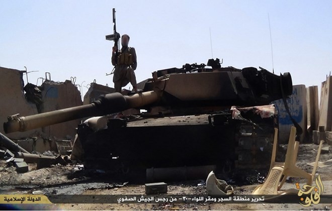 Một tay súng IS đứng trên một chiếc xe tăng bị phá hủy sau khi tấn công trại quân đội ở tỉnh Anbar. (Nguồn: ibtimes.co.in)