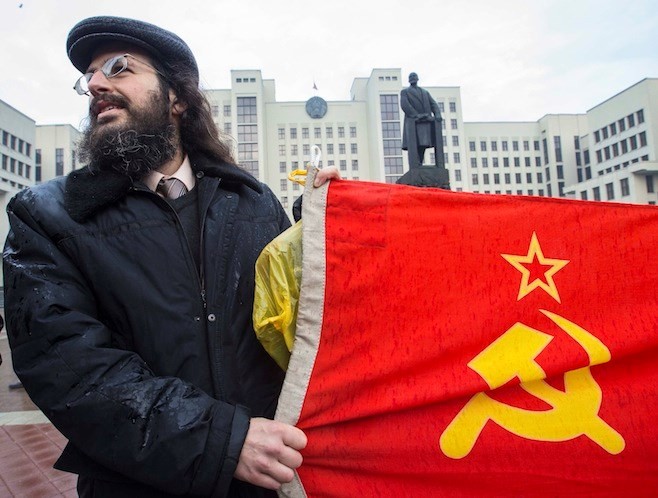 Một người cầm lá cờ Xô Viết đứng trước tượng đài Lenin ở Minsk, Belarus. Ảnh: Reuters. 