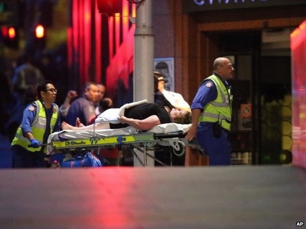 Cảnh sát Australia đưa người bị thương trong vụ bắt giữ con tin rời khỏi hiện trường. (Nguồn: AP)