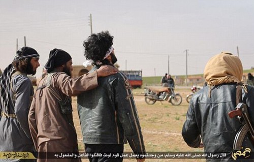 Phiến quân khoác vai một trong hai nạn nhân bị ném đá (thứ ba từ trái sang). Ảnh: IS Media/Twitter.