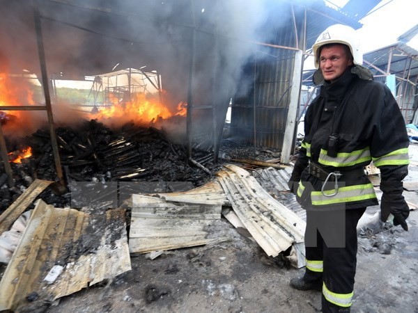 Lính cứu hỏa dập lửa đám cháy khu chợ ở Donetsk sau vụ pháo kích. (Nguồn: AFP/ TTXVN)