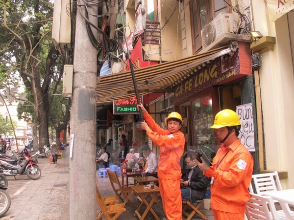 Nhân viên Công ty Điện lực Hoàn Kiếm ghi chỉ số công tơ điện bằng gậy gắn camera (Ảnh: Đức Duy/Vietnam+)