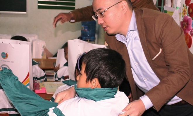 Ông Nguyễn Phan Huy Khôi, Giám đốc Đối ngoại, Tập đoàn Number 1 (Tân Hiệp Phát) mặc áo ấm cho một em nhỏ dân tộc Vân Kiều tại trường Tiểu học Trường Sơn, huyện Quảng Ninh.