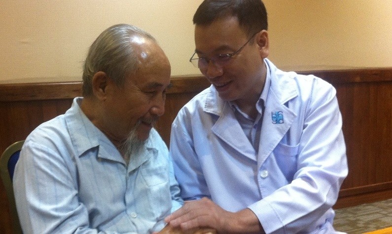 Ông C. đang trò chuyện với bác sĩ Định sau hơn 3 tuần được thay van động mạch chủ qua ống thông (TAVI), theo ông, trước đây ông không thể ngồi lâu và trò chuyện thoải mái được như vậy. Ảnh: Quốc Ngọc