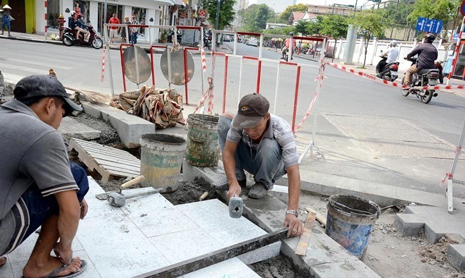 Công nhân lát gạch trên vỉa hè tại giao lộ Lê Thánh Tôn - Pasteur, quận 1, TPHCM. Ảnh: Zing