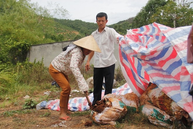 Người dân chọc thủng một bao tải chứa chất thải để kiểm tra bên trong. Ảnh: Thanh Trần. 