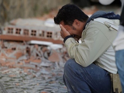 Một người đàn ông ôm mặt khóc bên đống đổ nát sau trận động đất ở Italia