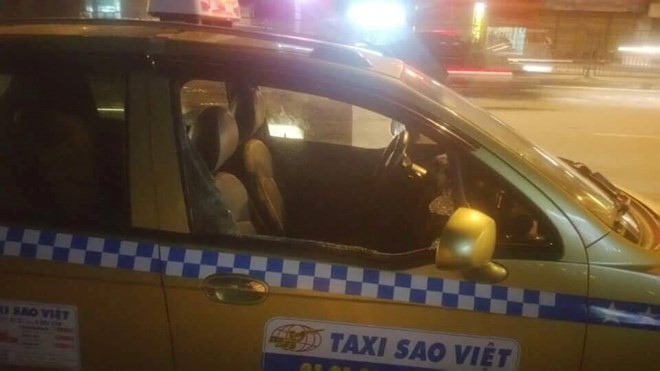 Chiếc xe taxi bị các đối tượng côn đồ đập phá. (Ảnh: PV/Vietnam+) 