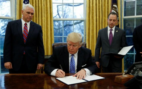 Ông Trump ký sắc lệnh hành pháp (executive order) dưới sự chứng kiến của Phó tổng thống - Mike Pence (trái) và Chánh Văn phòng Nhà Trắng - Reince Priebus tại Phòng Bầu dục ngày 23/1 (theo giờ Washington). Ảnh: Reuters