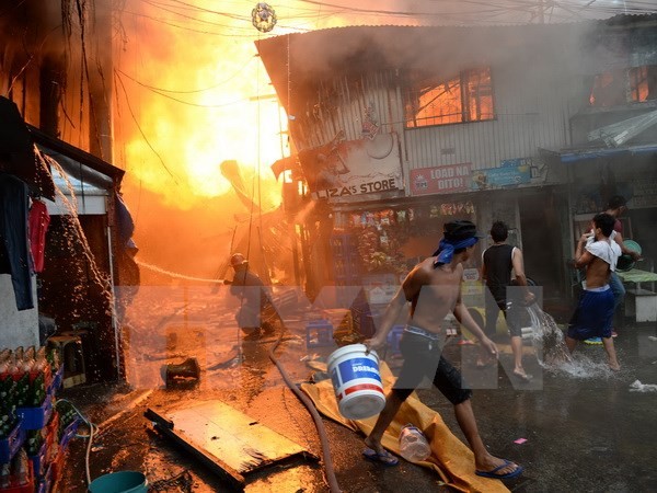 Nhân viên cứu hỏa và người dân địa phương nỗ lực khống chế đám cháy dữ dội tại một khu dân cư nghèo ở khu vực ngoại ô thủ đô Manila. (Ảnh: AFP/TTXVN)