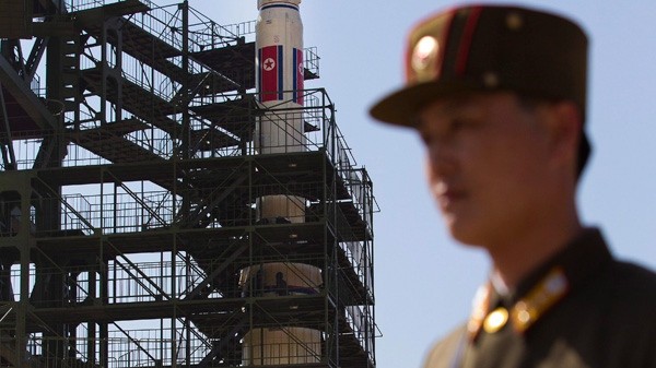 Lính Triều Tiên đứng trước một bệ phóng tên lửa.