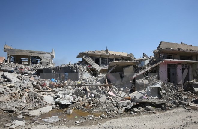 Người dân Iraq dọn dẹp những đống đổ nát sau các vụ không kích. (Nguồn: AFP/TTXVN)