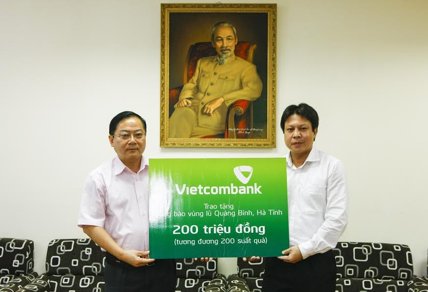 Đại diện Công đoàn Ngân hàng Vietcombank (bên phải) trao số tiền 200 triệu đồng đến bà con vùng lũ qua báo Tiền Phong. Ảnh: Như Ý 