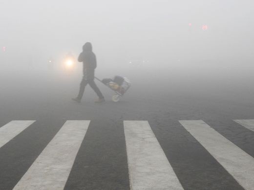 Người đi bộ ở Bắc Kinh bị sương mù nhấn chìm. Ảnh: AFP 