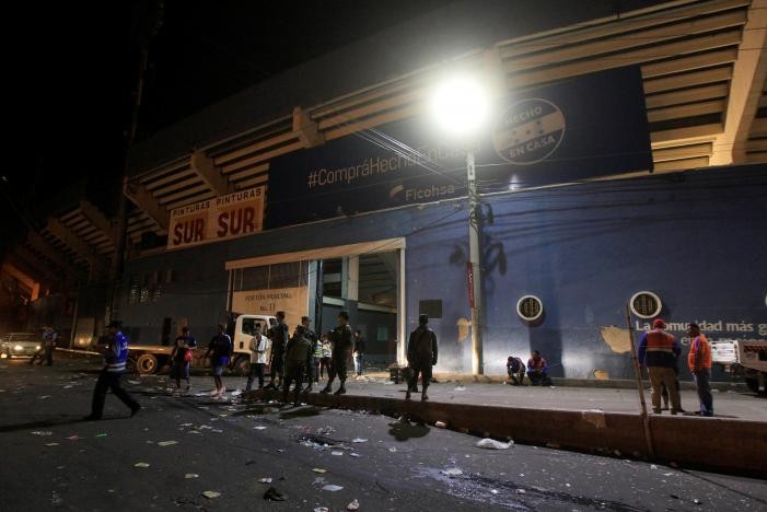 Cảnh sát đứng bên ngoài sân vận động sau sự cố hàng trăm người cố gắng vượt rào vào xem bóng đá ở Tegucigalpa. Ảnh: Reuters