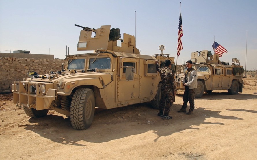 Chiến binh SDF đứng cạnh xe quân sự của Mỹ ở ngoại ô thị trấn Manbij, Aleppo, Syria, hồi tháng 3. Ảnh: AP