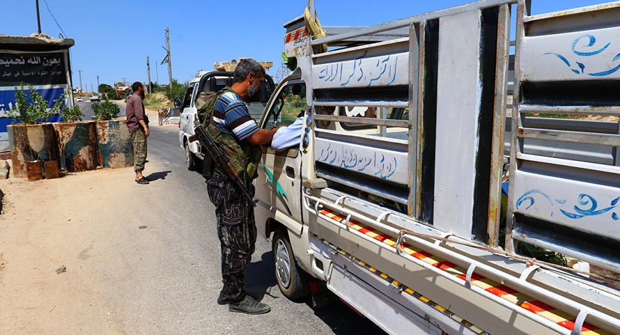 Các tay súng của liên minh các nhóm nổi dậy Jaish al Fateh kiểm tra xe tải tại tỉnh Idlib hôm 18/7. Ảnh: Reuters