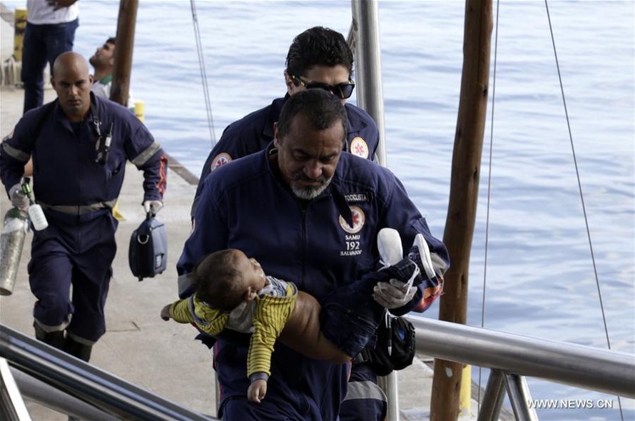 Nhân viên cứu hộ bế em bé trong vụ chìm tàu trên biển Brazil. Ảnh: AGENCIA ESTADO