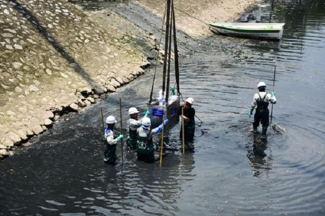 Các kỹ sư và công nhân vận chuyển máy sục khí Nano công nghệ Nhật xuống lòng sông Tô Lịch. Ảnh: Dân trí