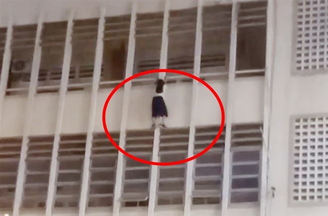 Nữ sinh đu ở lan can tầng 3 trường THCS Minh Đức. Ảnh cắt từ clip