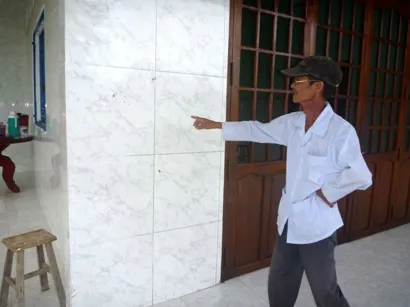 Ông Nguyễn Văn Hai chỉ nơi bọn côn đồ dội bom xăng vào làm bể gạch men ốp tường.