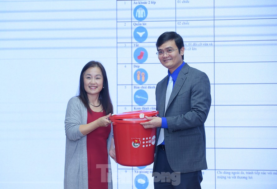 Anh Bùi Quang Huy tiếp nhận bộ đồ thiết yếu cho người cao tuổi ứng phó với lũ lụt từ bà Naomi Kitahara. Ảnh: Xuân Tùng