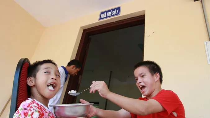 Hai em nhỏ tự đút cơm cho nhau ăn rất ngon lành. Ảnh: Minh Đức