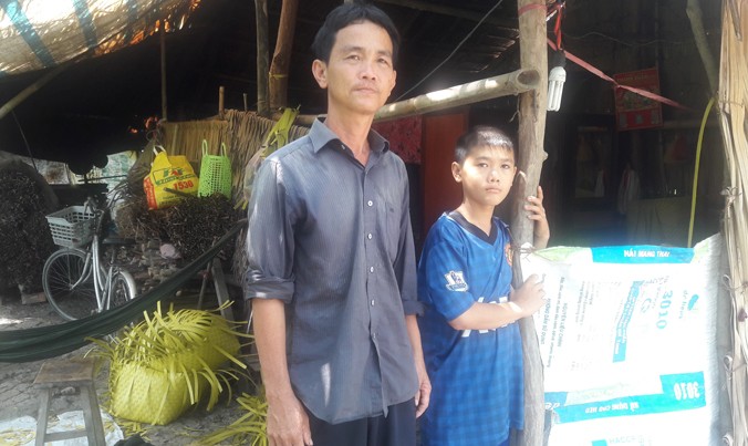 Anh Trương Văn Lợi và con trai bên túp lều lụp xụp.